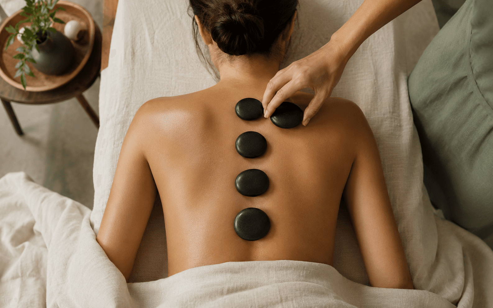 Warm massage stones being placed along a client's spine during a hot stone massage